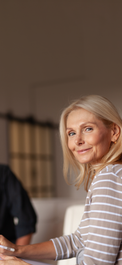 Femme blonde qui sourit avec un homme en arrière plan